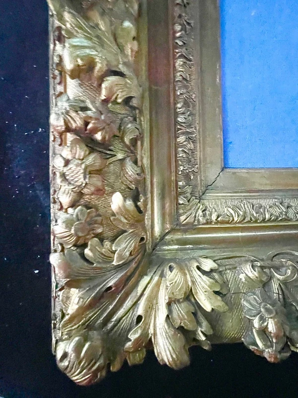 An ivory statue of Christ with a carved and gilded wooden frame featuring plant motifs.