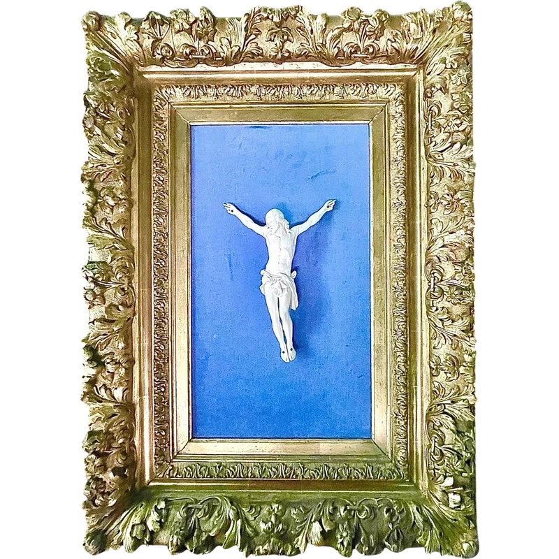 An ivory statue of Christ with a carved and gilded wooden frame featuring plant motifs.