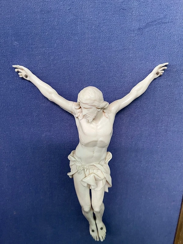 An ivory statue of Christ with a carved and gilded wooden frame featuring plant motifs.