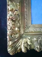 An ivory statue of Christ with a carved and gilded wooden frame featuring plant motifs.