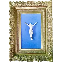 An ivory statue of Christ with a carved and gilded wooden frame featuring plant motifs.