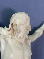 An ivory statue of Christ with a carved and gilded wooden frame featuring plant motifs.