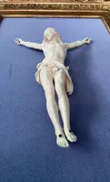 An ivory statue of Christ with a carved and gilded wooden frame featuring plant motifs.
