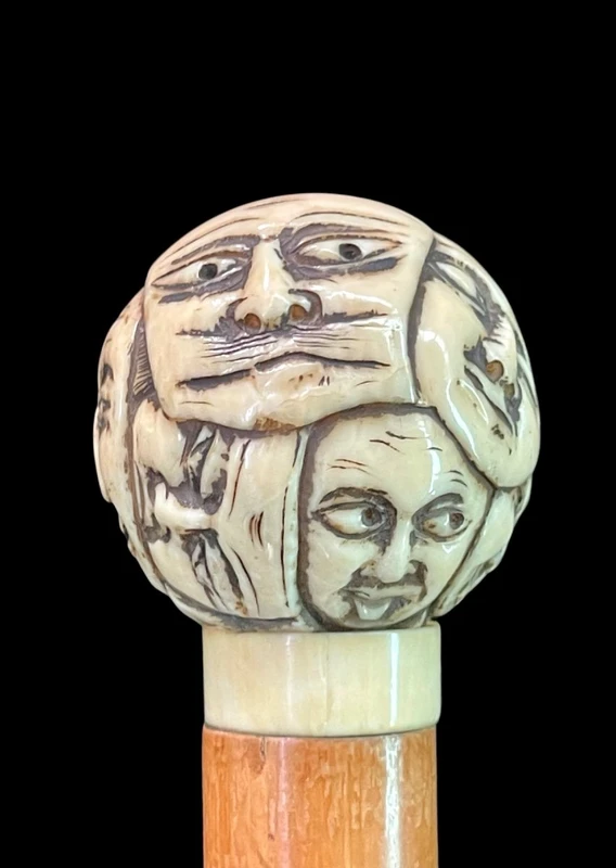 Cane with a round ivory knob carved with Commedia dell'Arte masks. Japan.