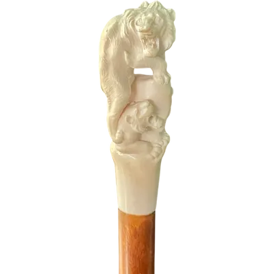 A walking stick with an ivory knob depicting two lions on a rock formation.