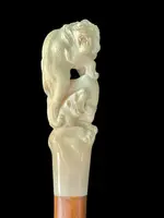 Bastone con pomolo in avorio raffigurante due leoni su formazione rocciosa.