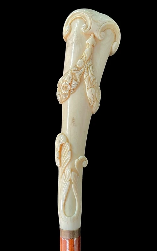 A walking stick with a vertical, curved ivory knob engraved with floral garlands and rocaille motifs.