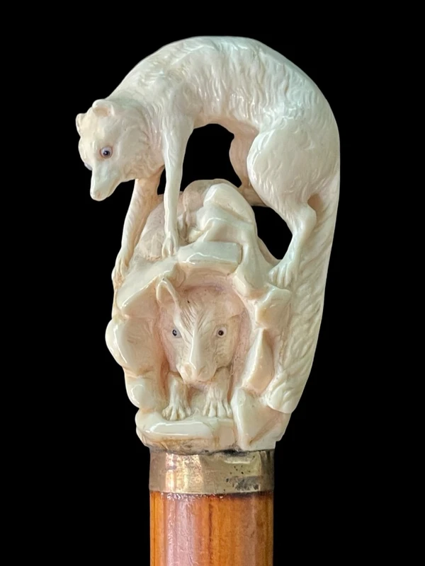 A walking stick with an ivory pommel depicting a wolf hunting prey hidden in a cave.