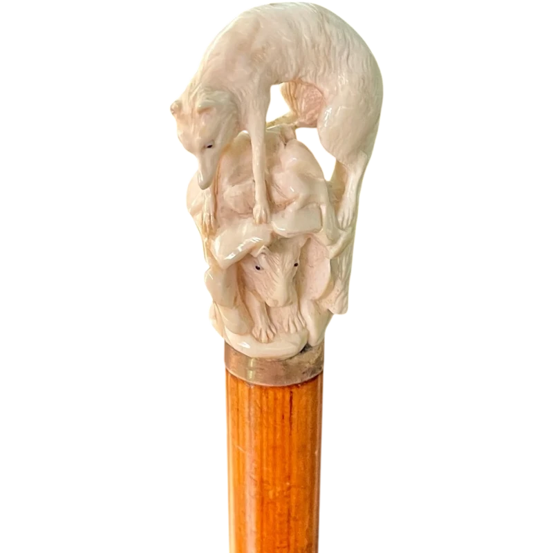 A walking stick with an ivory pommel depicting a wolf hunting prey hidden in a cave.