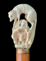 A walking stick with an ivory pommel depicting a wolf hunting prey hidden in a cave.