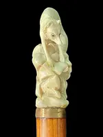 A walking stick with an ivory pommel depicting a wolf hunting prey hidden in a cave.
