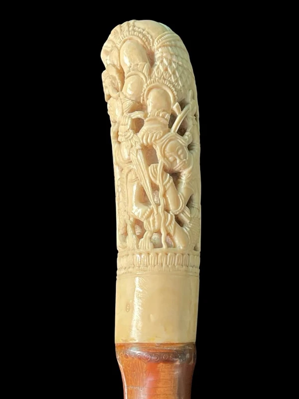 Cane with an ivory knob carved with figures and plant motifs; bamboo shaft.