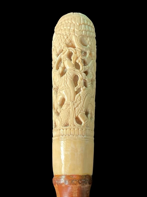 Cane with an ivory knob carved with figures and plant motifs; bamboo shaft.