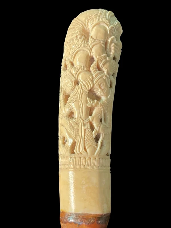 Cane with an ivory knob carved with figures and plant motifs; bamboo shaft.