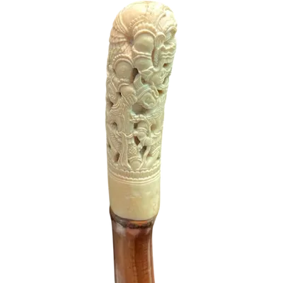 Cane with an ivory knob carved with figures and plant motifs; bamboo shaft.