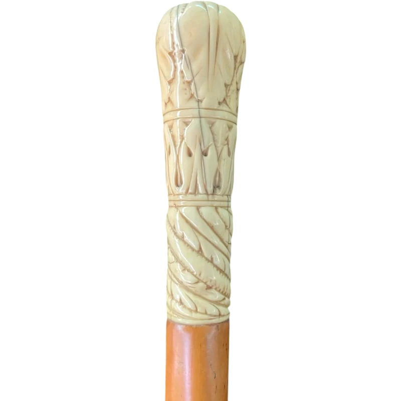 A walking stick with a spherical ivory pommel engraved with stylized plant motifs.