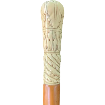 A walking stick with a spherical ivory pommel engraved with stylized plant motifs.