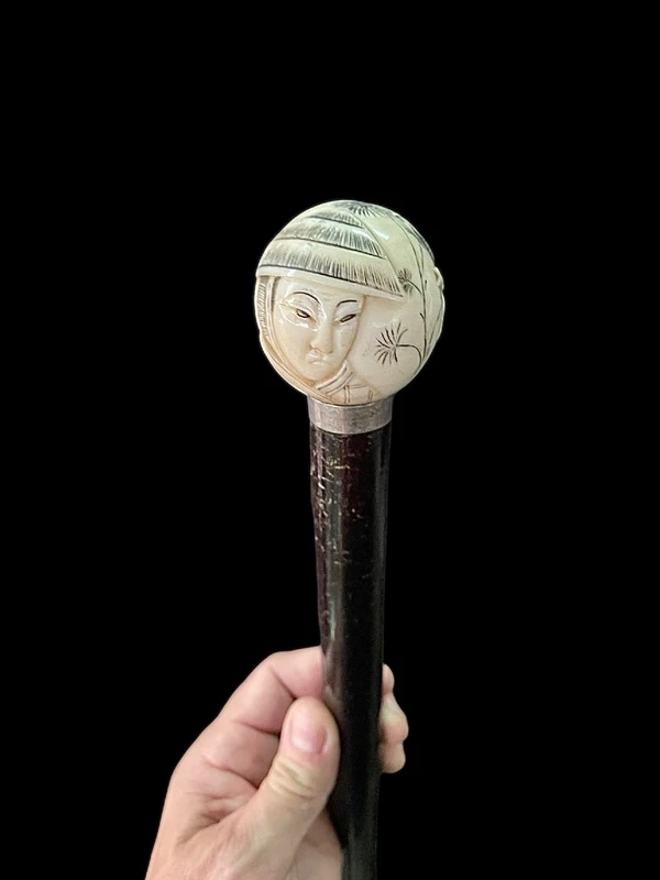 A walking stick with a round ivory knob engraved with Japanese figures.