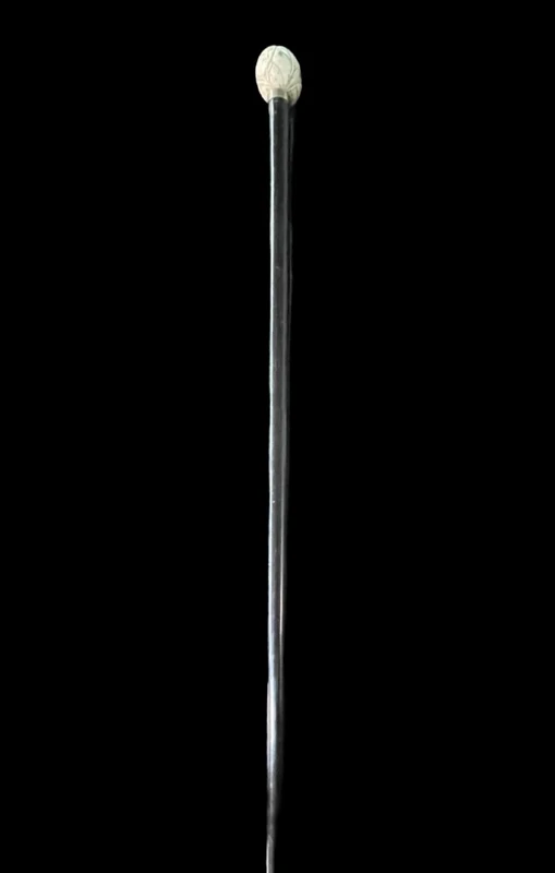 A walking stick with a round ivory knob engraved with Japanese figures.