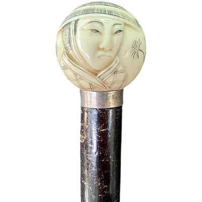 A walking stick with a round ivory knob engraved with Japanese figures.