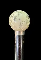 A walking stick with a round ivory knob engraved with Japanese figures.