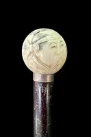 A walking stick with a round ivory knob engraved with Japanese figures.