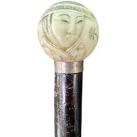 A walking stick with a round ivory knob engraved with Japanese figures.