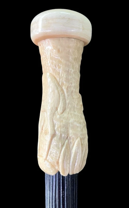 A walking stick with a spherical ivory pommel featuring a deer figure engraved in bas-relief.