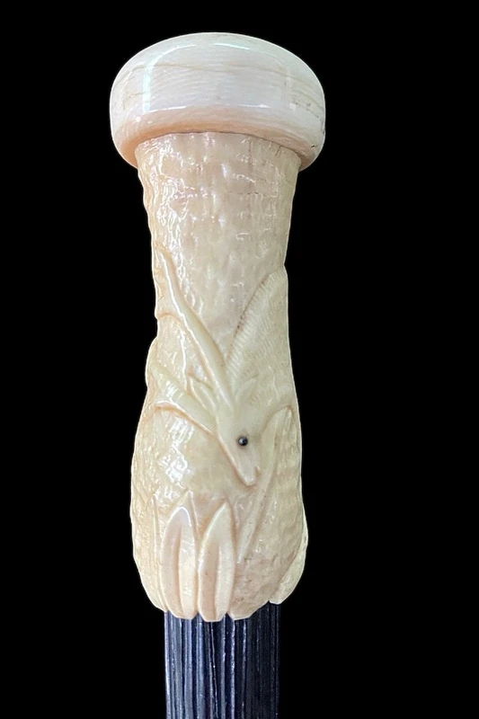 A walking stick with a spherical ivory pommel featuring a deer figure engraved in bas-relief.