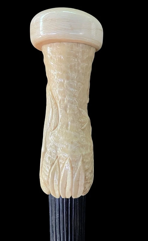 A walking stick with a spherical ivory pommel featuring a deer figure engraved in bas-relief.