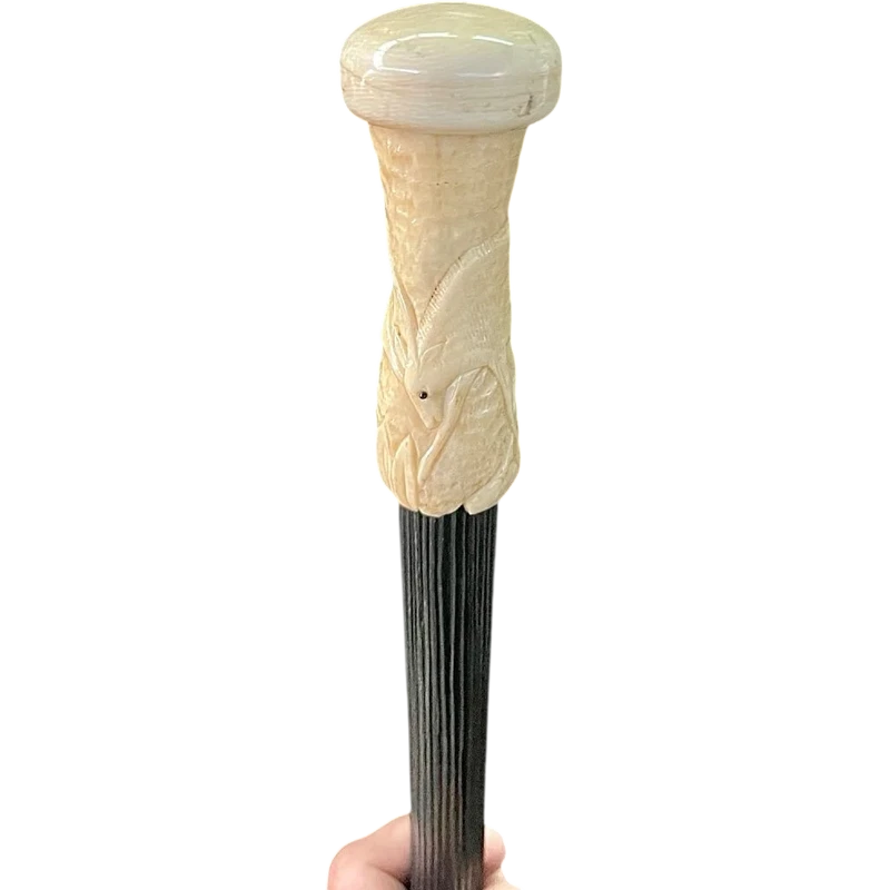 A walking stick with a spherical ivory pommel featuring a deer figure engraved in bas-relief.