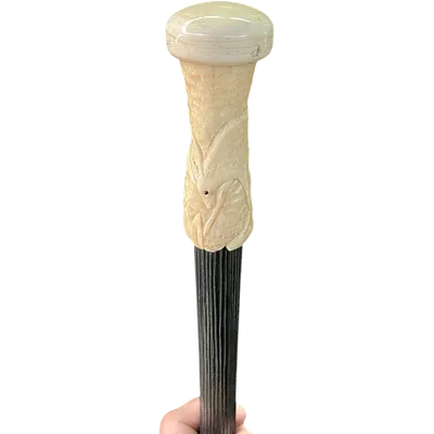 A walking stick with a spherical ivory pommel featuring a deer figure engraved in bas-relief.