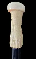 A walking stick with a spherical ivory pommel featuring a deer figure engraved in bas-relief.