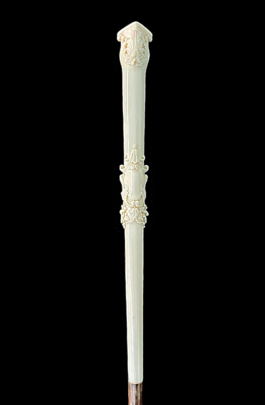 An evening cane with an ivory knob featuring a relief shield and rocaille motifs.