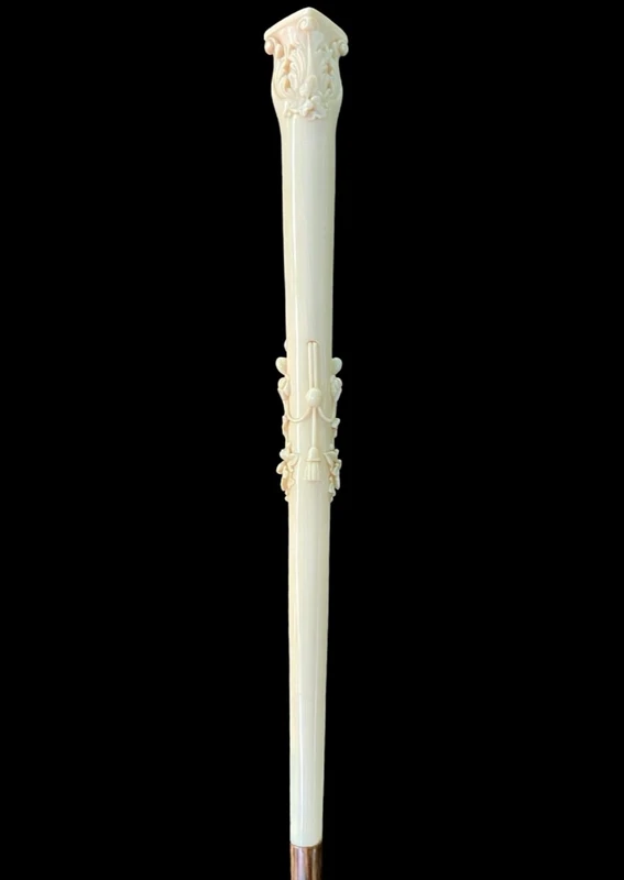 An evening cane with an ivory knob featuring a relief shield and rocaille motifs.