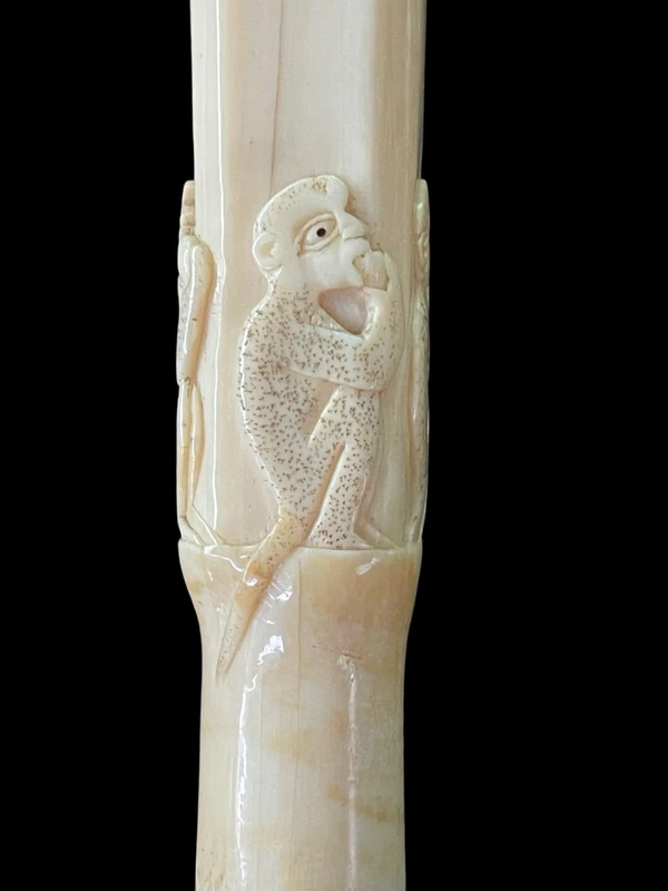An evening cane with a square-section ivory knob featuring three monkeys engraved in bas-relief.