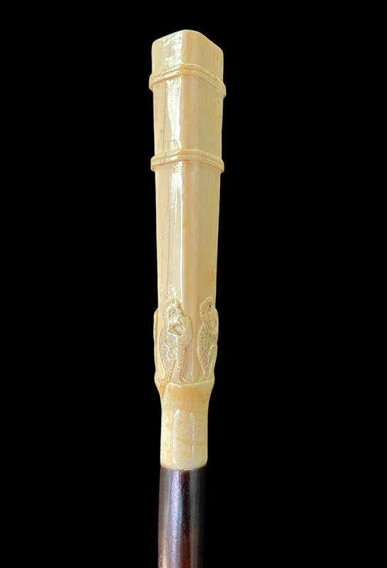 An evening cane with a square-section ivory knob featuring three monkeys engraved in bas-relief.