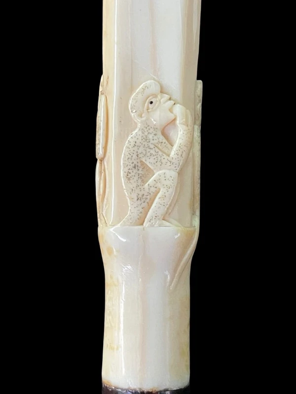 An evening cane with a square-section ivory knob featuring three monkeys engraved in bas-relief.