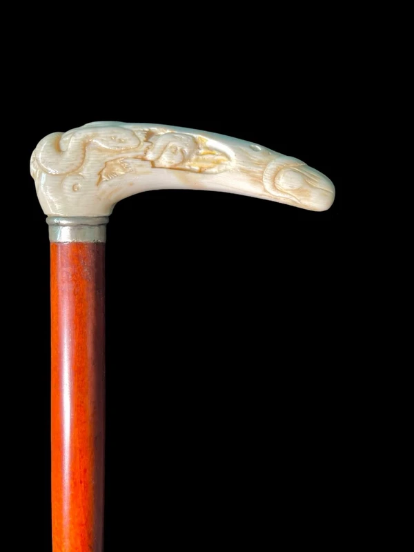 A staff with a side handle in the shape of a tau, made of ivory and depicting a snake hunting inside a tree trunk.