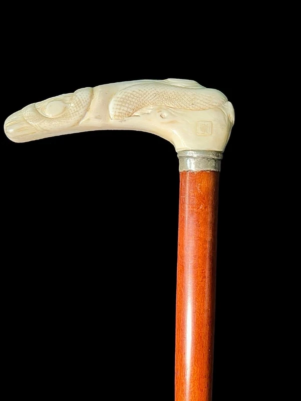 A staff with a side handle in the shape of a tau, made of ivory and depicting a snake hunting inside a tree trunk.