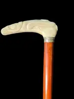 A staff with a side handle in the shape of a tau, made of ivory and depicting a snake hunting inside a tree trunk.