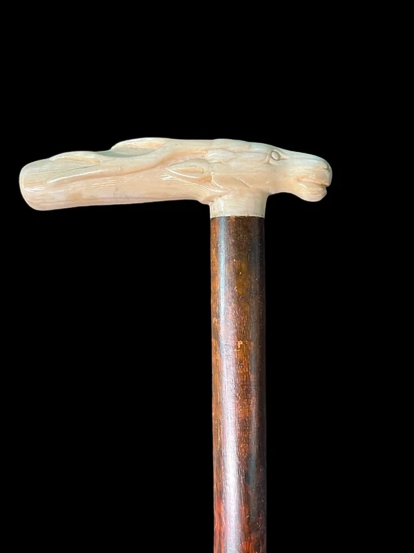 A walking stick with a side-mounted tau-shaped handle depicting a deer's head.