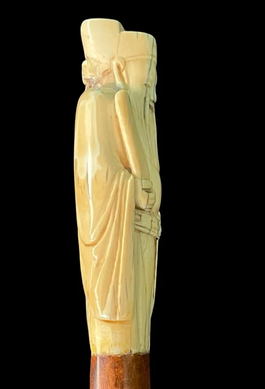 A walking stick with an ivory pommel depicting an Asian male figure.