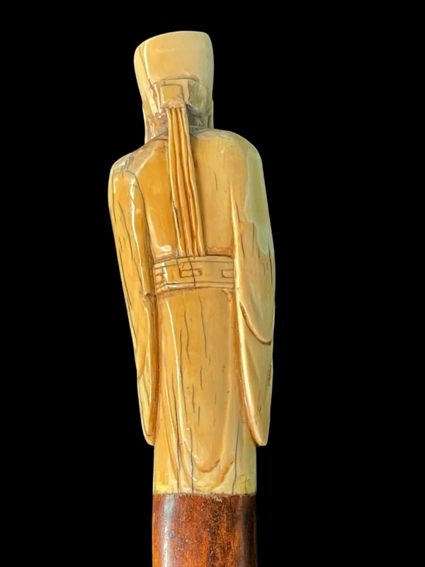 A walking stick with an ivory pommel depicting an Asian male figure.