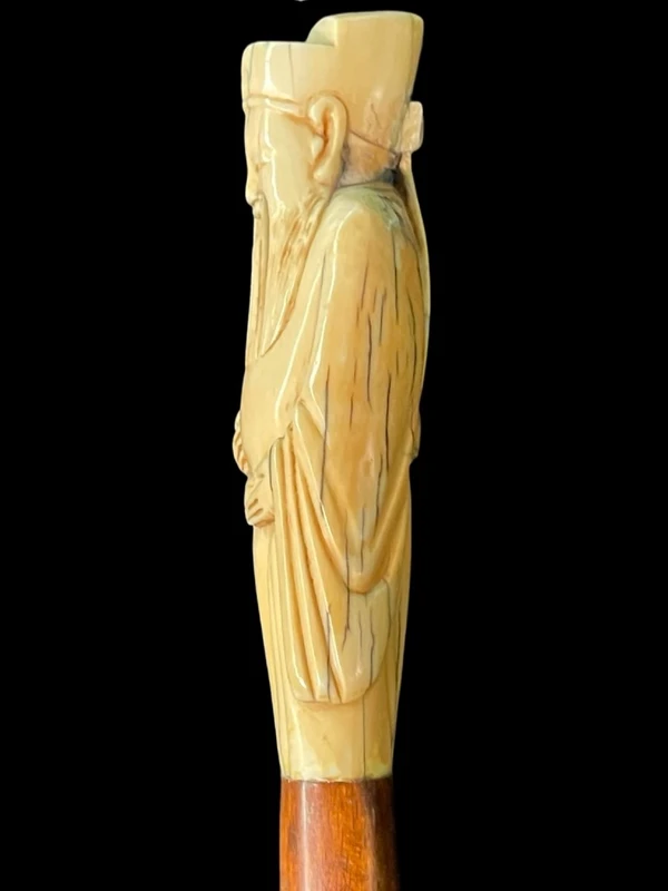 A walking stick with an ivory pommel depicting an Asian male figure.