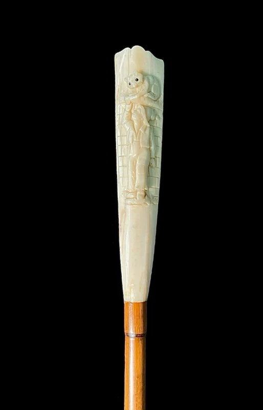A walking stick with a "plume" knob featuring a high-relief figure of a child playing with a cat.