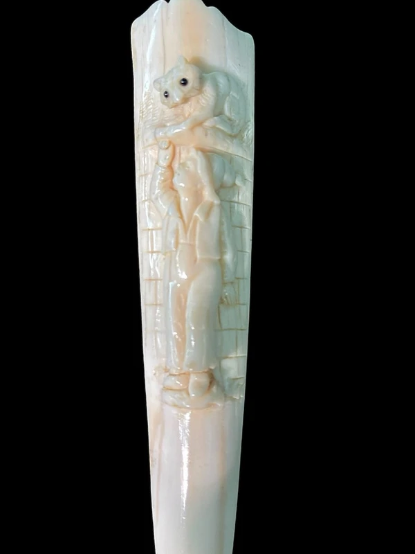 A walking stick with a "plume" knob featuring a high-relief figure of a child playing with a cat.
