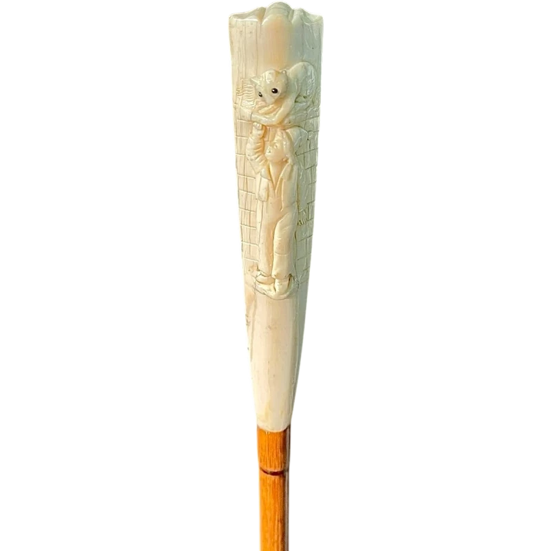 A walking stick with a "plume" knob featuring a high-relief figure of a child playing with a cat.