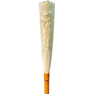 A walking stick with a "plume" knob featuring a high-relief figure of a child playing with a cat.