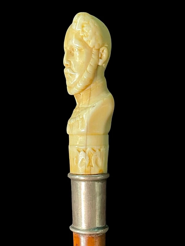Cane with an ivory knob depicting a male bust. The shaft is made of rattan.